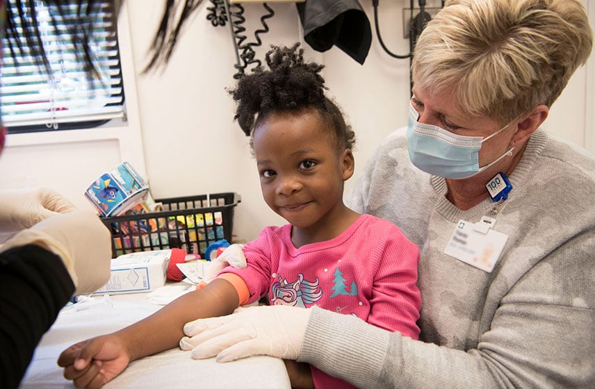 克利夫兰诊所的护士坐在小女孩身边接受注射。
