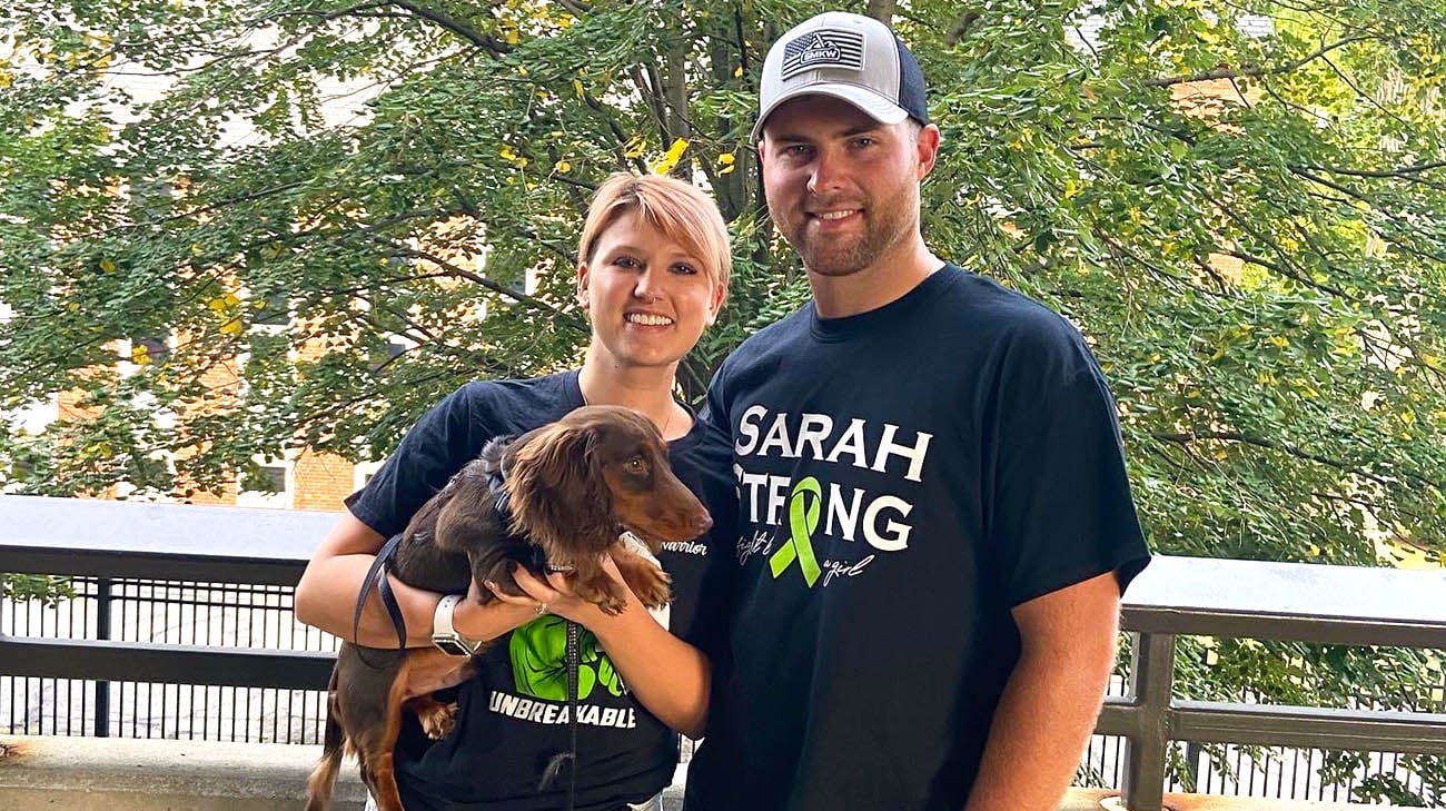 莎拉和她的丈夫麦肯齐，还有他们的狗狗库珀，在为白血病和淋巴瘤协会举办的“点亮黑夜”活动中。